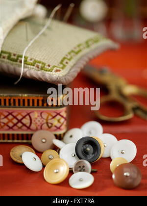 Boutons Vintage et pin cushion sur table rouge Banque D'Images