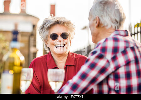 Senior couple on city rooftop garden chatting et relaxant avec du vin blanc Banque D'Images