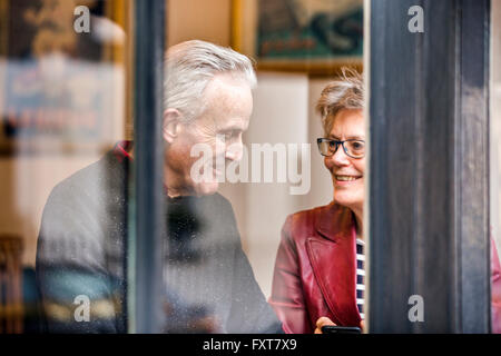 Senior couple sitting at cafe siège de fenêtre chatting Banque D'Images