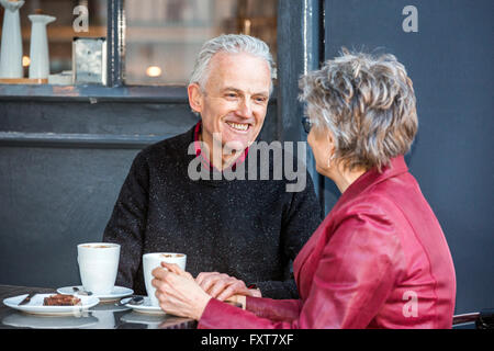 Senior couple at sidewalk cafe boire du café et à discuter Banque D'Images