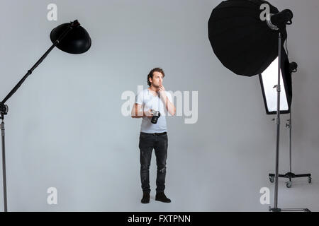 Pensive photographe professionnel masculin en studio avec du matériel Banque D'Images