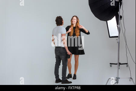 Photographe homme parlant avec modèle féminin en studio avec des équipements Banque D'Images