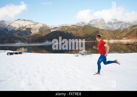 Homme runner le long d'un lac couvert de neige, le lac Kawaguchiko, le Mont Fuji, Japon Banque D'Images