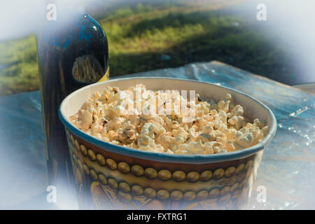 Sur la table, du pop-corn dans de grands verres et une bouteille de vin. Le camping. Banque D'Images