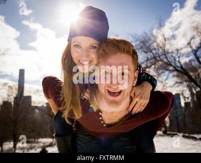 Portrait of young man giving girlfriend a piggy back in Central Park, New York, USA Banque D'Images