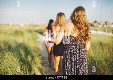 Vue arrière des femmes porteuses boîtes à pizza sur sentier du littoral Banque D'Images