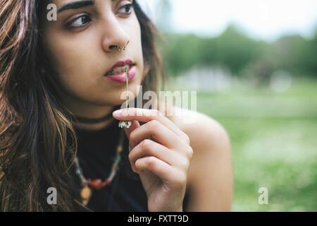 Femme avec anneau dans le nez de mâcher de l'herbe à l'écart Banque D'Images