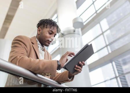 Jeune homme d'affaires en gare à l'aide d'écran tactile de tablette numérique Banque D'Images