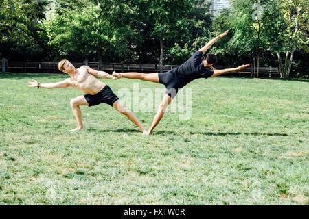 Deux hommes pratiquant le yoga pied position hold in park Banque D'Images