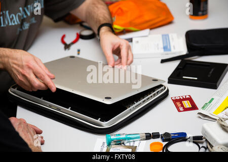 Hackney, Londres, Royaume-Uni. Vue détaillée de redémarrer partie volontaire David Mery dépose de la base d'un MacBook Pro d'Apple. Banque D'Images