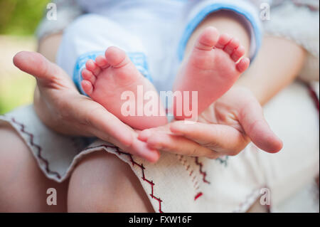 Maman détient les jambes d'un petit enfant Banque D'Images