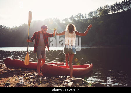 Jeune homme femme aidant à l'étape dans le kayak. Couple pour une balade en canoë sur le lac. Banque D'Images