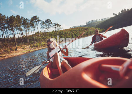 Happy young couple canoë sur le lac. L'homme et la femme du kayak sur une journée d'été. Banque D'Images