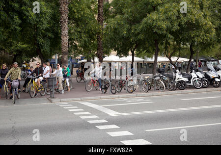Les gens, les touristes, les sections locales sur les bicyclettes en attente de feu de circulation à l'intersection à Barcelone en Espagne. Banque D'Images