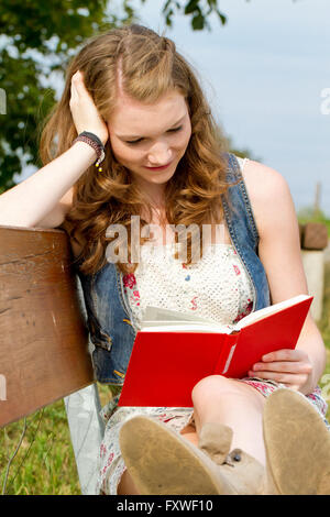 Jeune femme lisant un livre dans la nature Banque D'Images