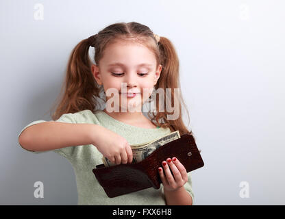 Petit enfant cute girl taking dollars de la mère porte-monnaie et à heureux sur fond bleu Banque D'Images