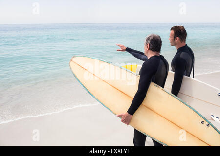 Père et fils debout avec surf et pointant à une distance Banque D'Images