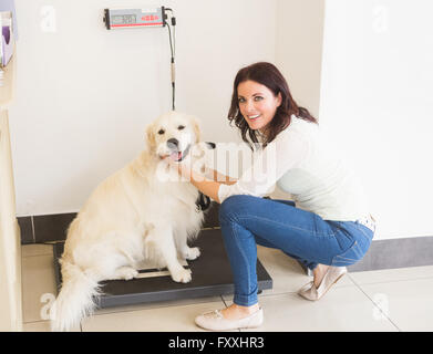 Femme pesant son chien sur une balance vétérinaire Banque D'Images