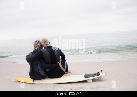 Vue arrière du couple sitting on surfboard Banque D'Images