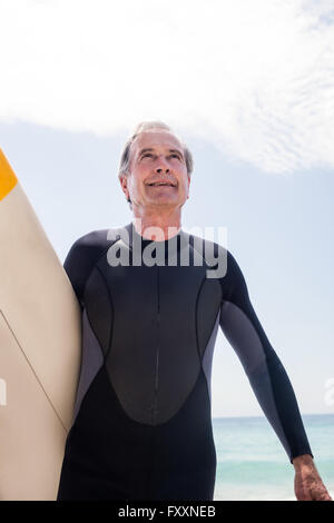 Portrait of senior man in wetsuit holding a surfboard Banque D'Images