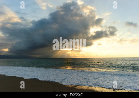 Coucher de soleil de l'océan est un brillant éclat de rayons de soleil briser un énorme nuage au-dessus de la pendaison d'un magnifique paysage marin. Banque D'Images