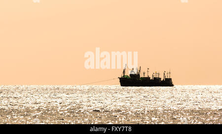 La silhouette du groupe de bateaux de pêche qui flottent sur l'eau en agitant avec fond de ciel de coucher du soleil Banque D'Images