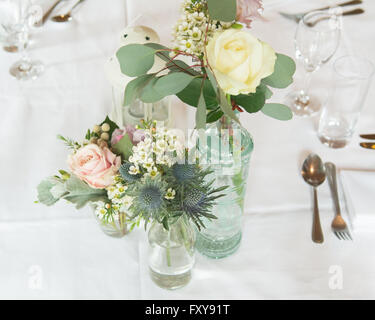 Set de table pour un mariage ou un événement avec des arrangements de fleurs en bouteilles vintage Banque D'Images