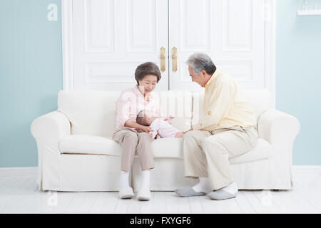 Couple assis sur un canapé en prenant soin du bébé couché sur la table Banque D'Images