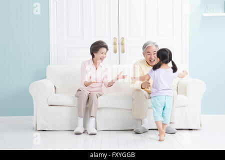 Couple assis sur un canapé se sentir heureux de voir leur petite-fille Banque D'Images