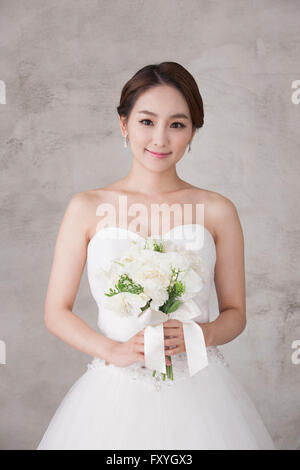 Bride holding a bouquet et fixant l'avant avec un sourire Banque D'Images