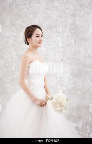 Bride holding bouquet dans une main et regardant de côté avec un sourire Banque D'Images