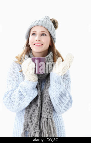 Woman in winter clothes holding une tasse et jusqu'à la avec un sourire Banque D'Images