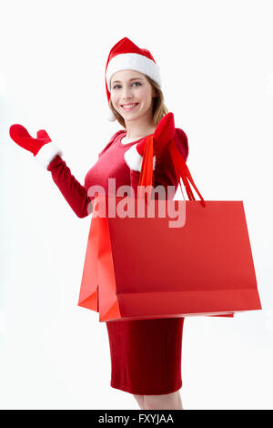 Femme en costume rouge Santa holding shopping bags Banque D'Images