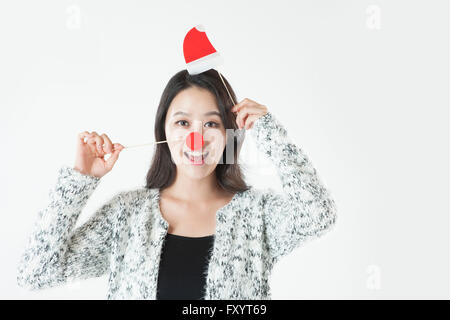 Portrait of young smiling woman putting sur santa hat et le nez de deer regarder/ Banque D'Images