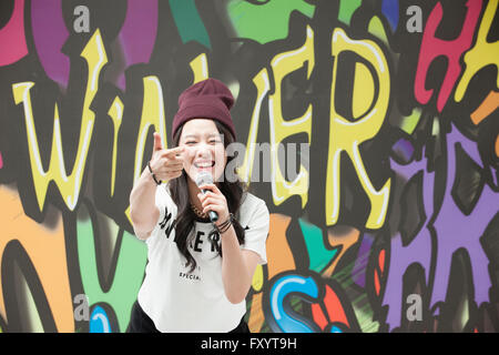 Portrait of young smiling woman in style hip-hop tenant un microphone et des gestes avec les doigts Banque D'Images