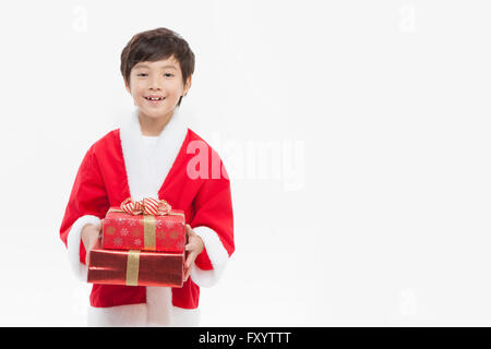 Portrait of smiling boy in Santa's clothes holding boîtes empilées à présenter avant Banque D'Images