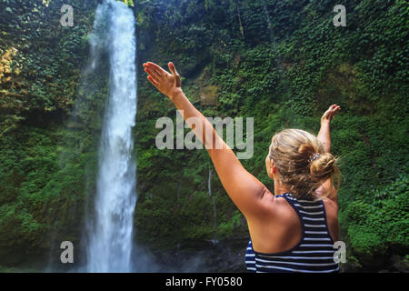 Jeune femme heureuse dans un camp de la diffusion et de profiter de la nature mains chute d'eau douce qui voyagent dans la forêt tropicale de Bali. Banque D'Images
