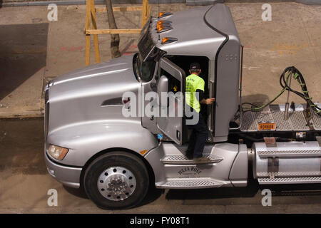 Chauffeur de camion de l'opérateur propriétaire debout à la porte ouverte d'un gros camion Kenworth semi-remorques stationnés sur une rue de la ville Banque D'Images