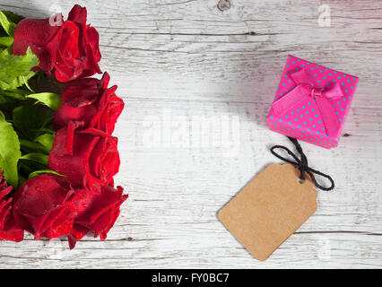 Roses rouges et roses petite boîte-cadeau avec balise vide sur la table rustique en bois blanc. Vue de dessus avec l'exemplaire de l'espace. Banque D'Images