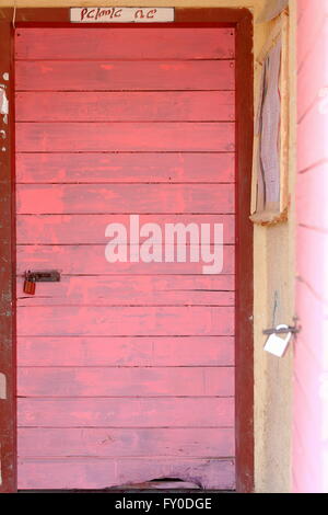 Peint en rose-cadenas fermé les portes en bois sur les murs couleur moutarde de l'école locale à Berahile-Ethiopia-Danakil ville-loin Banque D'Images