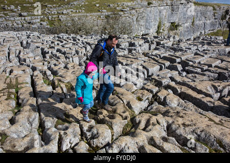 Un homme et sa fille naviguer les pavages calcaires sur la falaise à Malham Cove dans le North Yorkshire, Angleterre Banque D'Images