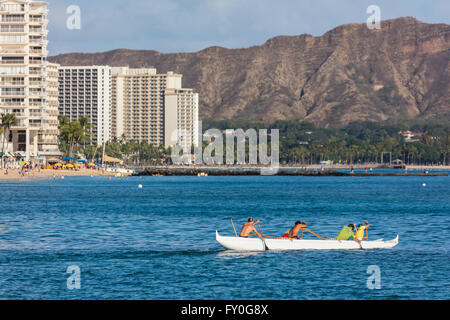 Les gens d'une pagaie canoë dans Wakiki Hawaiian ocean bay. Banque D'Images