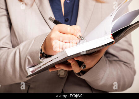 Close-up of female hands holding un agend estimates et rédaction d'une note sur le papier Banque D'Images