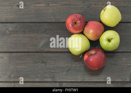 Groupe des pommes rouges et vertes est posé sur une table en bois en milieu rural. Édité comme une photo couleur rustique par effet splash. Banque D'Images