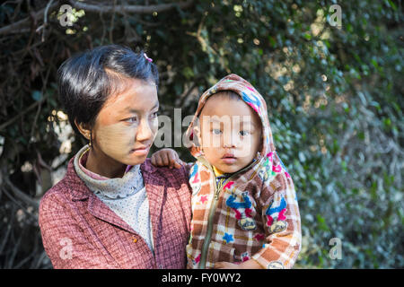 Femme birmane local avec écran solaire thanaka porter un bébé garçon dans un village sur le fleuve Irrawaddy, Myanmar (Birmanie) Banque D'Images