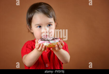 Little girl holding donuts tourner en studio Banque D'Images
