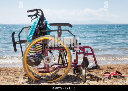 Fauteuil roulant sur la plage contre bleu de la mer en été Banque D'Images