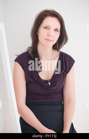 Femme assise à l'intérieur d'accueil. Image vie de jeune femme montrant la fierté, la relaxation et le contentement. Banque D'Images