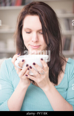 Woman holding tea cup dans votre intérieur. Concept de relaxation, prendre une pause et de tranquillité. Image Style de vie de contemplation. Banque D'Images