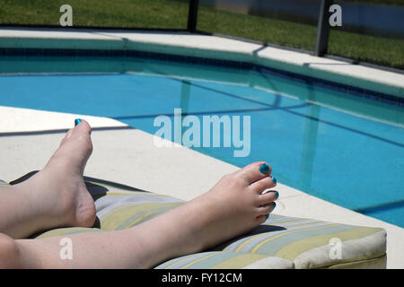 Pieds d'une femme mature de porter du vernis à ongles sur ses orteils pour correspondre à la piscine de couleur. Avril 2016